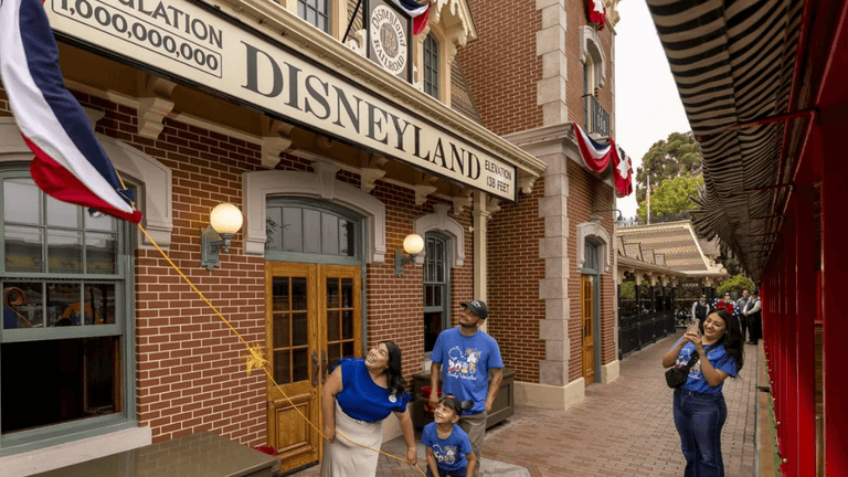 Family raises an anniversary flag outside Disneyland Railroad Main Street Station in Anaheim.