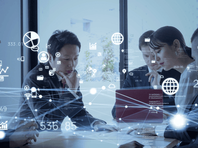 Business team collaborating around a table with digital network, data, cloud, and analytics graphics overlaid.