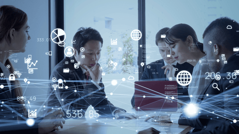 Business team collaborating around a table with digital network, data, cloud, and analytics graphics overlaid.
