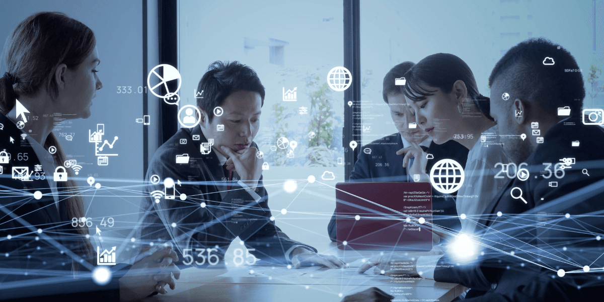 Business team collaborating around a table with digital network, data, cloud, and analytics graphics overlaid.