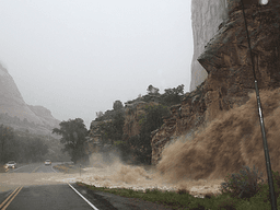 Mudslide cascading from a cliff onto a rain-soaked road during a storm