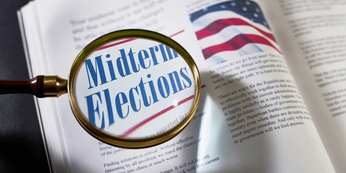 Magnifying glass over a page featuring the words "Midterm Elections" and an American flag