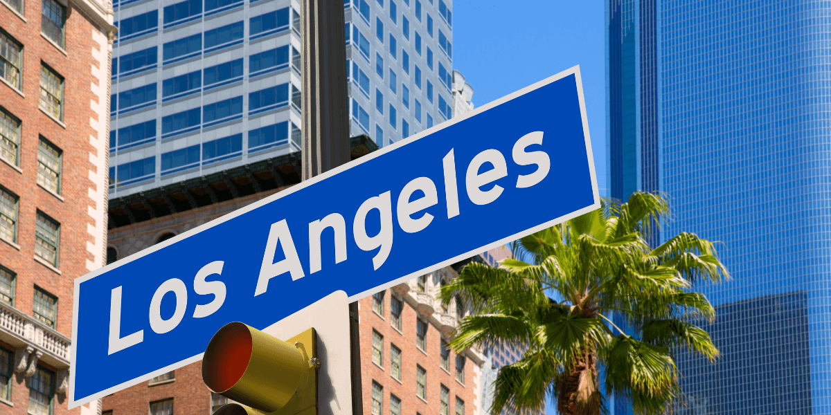 Los Angeles street sign with palm tree and skyscrapers in the background