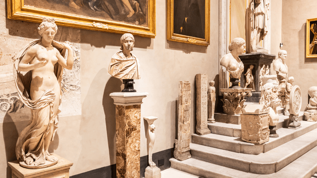 Interior of a museum showcasing classical sculptures and paintings along the walls