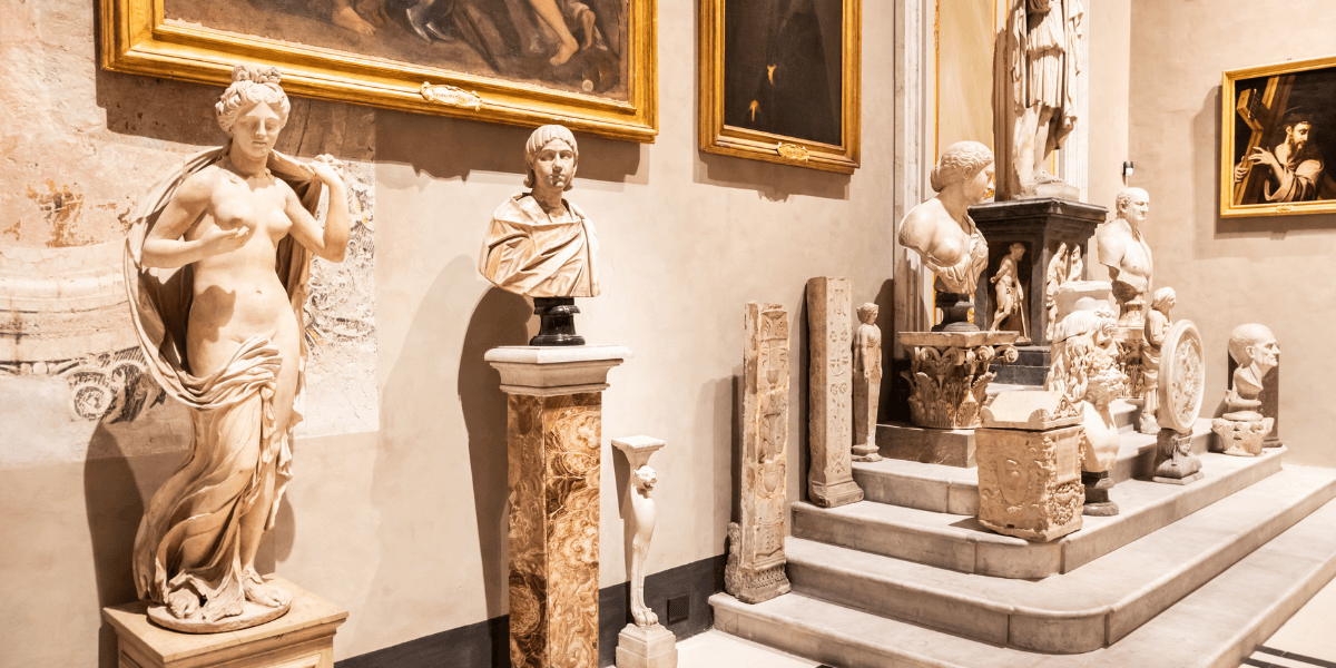 Interior of a museum showcasing classical sculptures and paintings along the walls