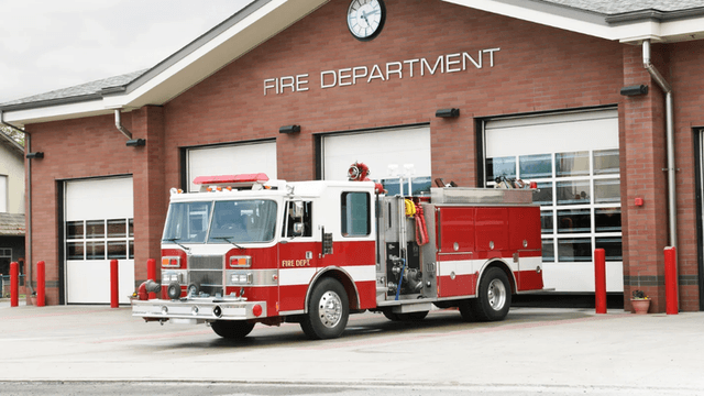 A fire truck parked in front of a fire department building with closed garage doors