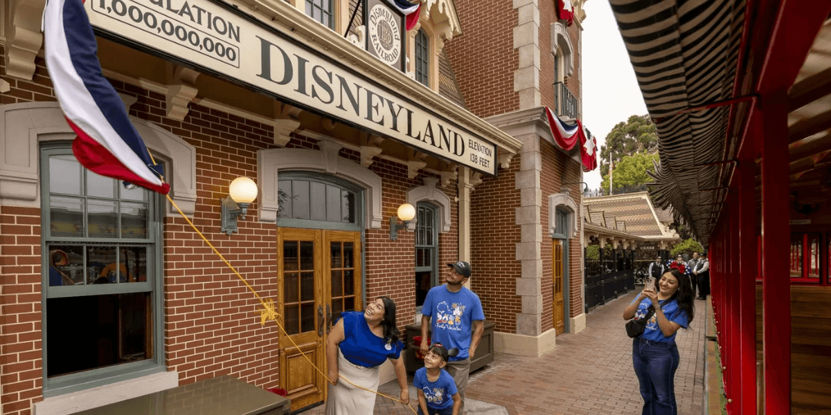 Family raises an anniversary flag outside Disneyland Railroad Main Street Station in Anaheim.