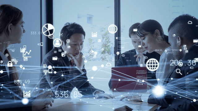 Business team collaborating around a table with digital network, data, cloud, and analytics graphics overlaid.