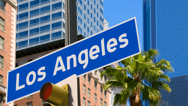 Los Angeles street sign with palm tree and skyscrapers in the background